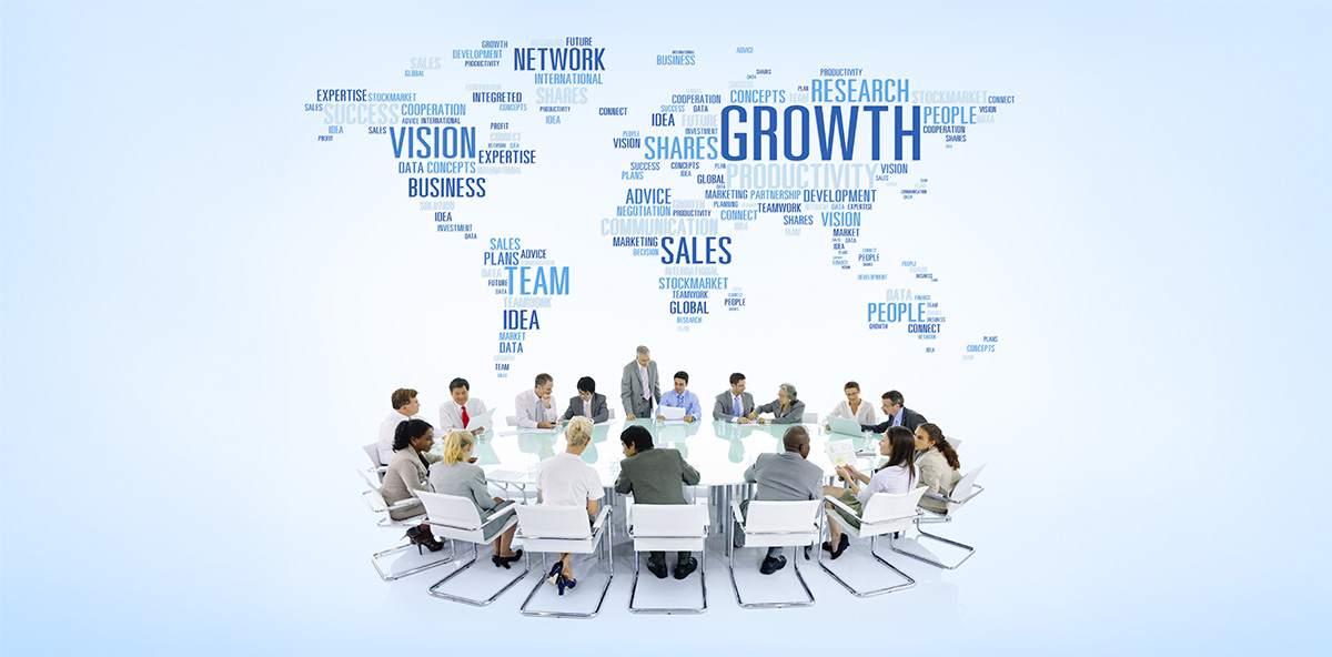 PartnerOps global strategy meeting with diverse business team seated around a roundtable, set against a world map formed by words like growth, vision, sales, and teamwork